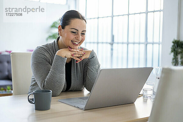 Lächelnde Geschäftsfrau bei einer Videokonferenz mit Laptop bei der Arbeit zu Hause