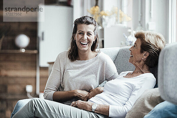Lachende Frau  die mit ihrer Großmutter auf dem Sofa zu Hause sitzt