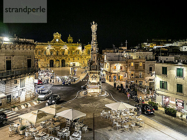 Italien  Provinz Brindisi  Ostuni  Säule des heiligen Orontius inmitten des beleuchteten Stadtplatzes bei Nacht