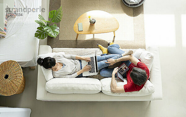 Ehepaar entspannt sich auf dem Sofa im heimischen Wohnzimmer