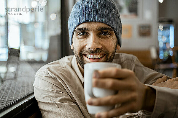 Glücklicher erwachsener Mann mit Kaffeetasse in einem Cafe