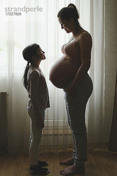 Schwangere Mutter mit Tochter zu Hause stehend