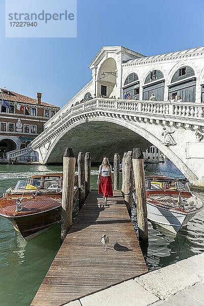 Junge Frau mit rotem Kleid an einem Steg mit Booten  Canal Grande  Rialto Brücke  Venedig  Venetien  Italien  Europa