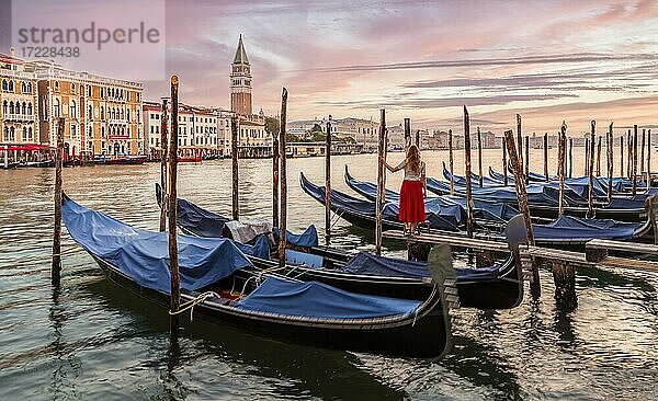 Frau mit roten Kleid blickt auf Venedig  Abendstimmung  Sonnenuntergang am Canal Grande  Gondeln am Pier  Glockenturm des Campanile  Venedig  Region Venetien  Italien  Europa