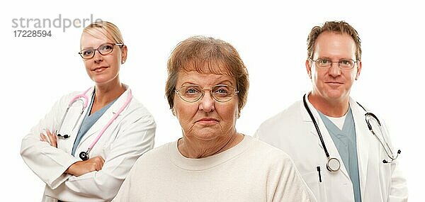 Besorgte ältere Frau mit Ärzten hinter isoliert auf einem weißen Hintergrund