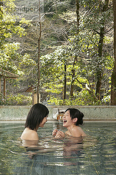 Glückliche junge Frauen Freunde lachend im Einweichen Pool bei Onsen