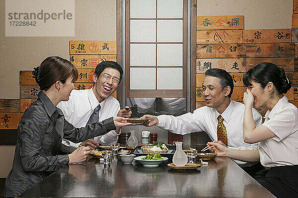 Glückliche japanische Geschäftsleute genießen Sushi Mittagessen im Restaurant