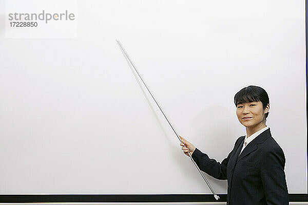 Porträt selbstbewusste Geschäftsfrau mit Zeiger am Whiteboard