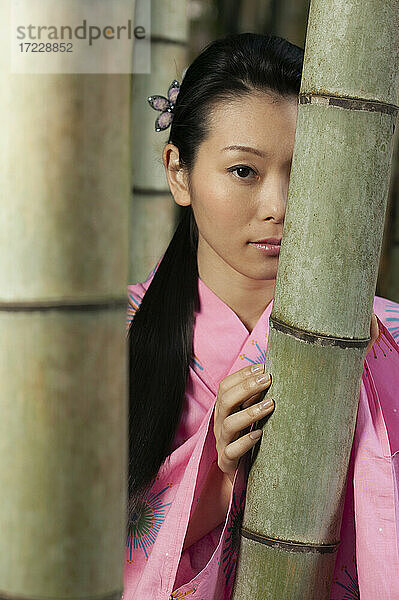 Porträt schöne junge Frau in rosa Kimono an Bambusbäumen