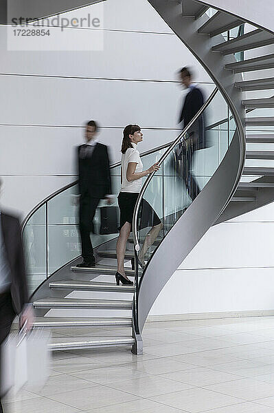 Junge Geschäftsfrau aufsteigend Wendeltreppe im Büro