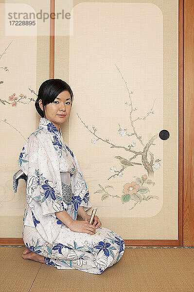 Porträt schöne junge japanische Frau im Kimono an gemalter Tür