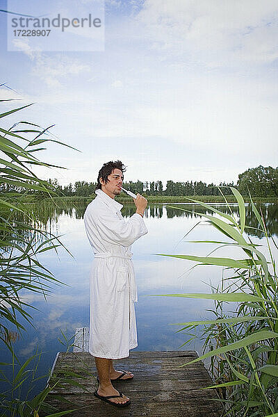 Mann im Bademantel beim Zähneputzen am ruhigen See