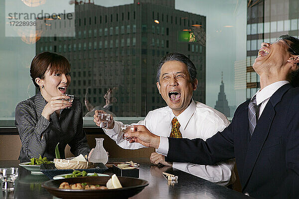 Glückliche Geschäftsleute lachen beim Mittagessen im Hochhausrestaurant