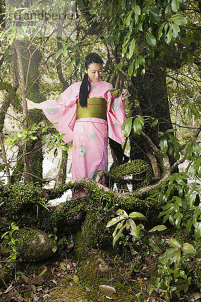 Junge Frau in rosa Kimono unter schönen Bäumen