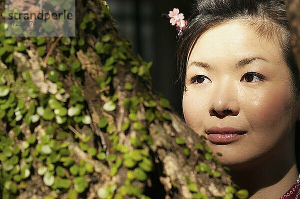 Close up Porträt schöne junge Frau schaut weg hinter Baum