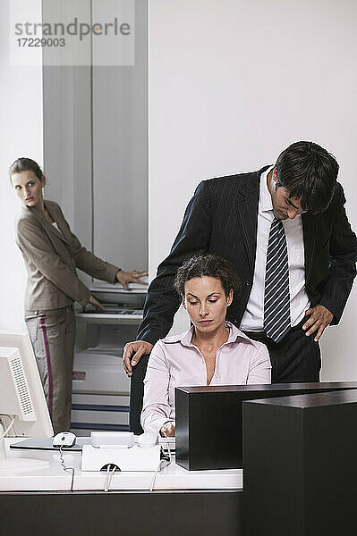 Geschäftsmann schaut über die Schulter einer Geschäftsfrau im Büro