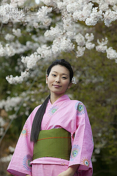 Porträt schöne junge Frau im Kimono unter Kirschblüten