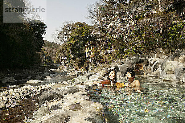 Glückliche junge Frauen  die im sonnigen Onsen-Pool eintauchen  Izu  Japan