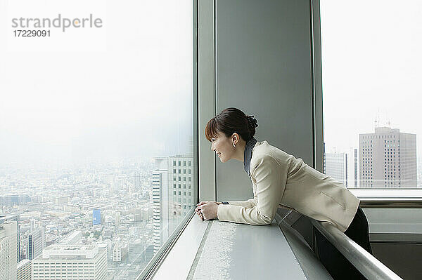 Geschäftsfrau mit Blick auf die Stadt aus dem Hochhaus Büro