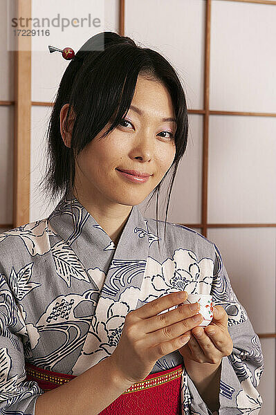 Porträt schöne junge Frau im japanischen Kimono mit Tee