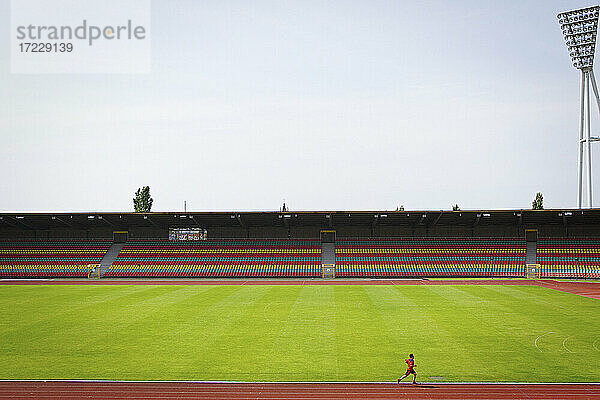 Mann läuft auf Bahn bei sonnigem Fußballstadion