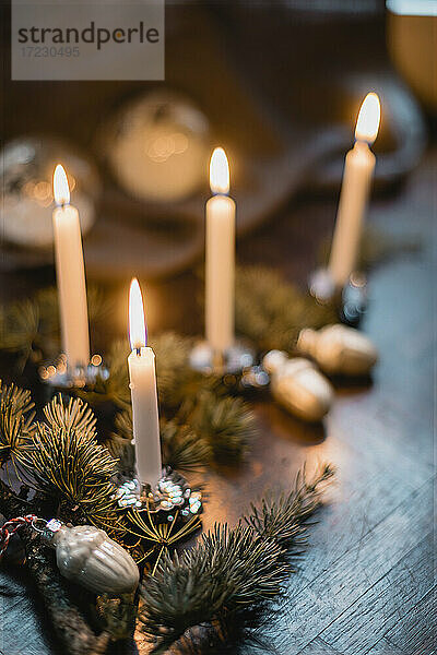 Weihnachtliche Tischdekoration mit Nadelzweigen und brennenden Kerzen