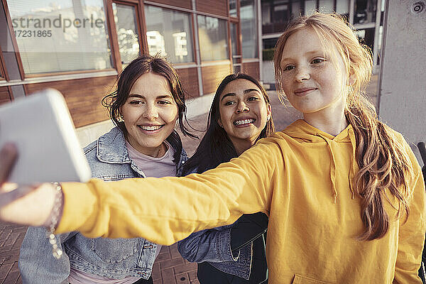 Lächelnde Freundinnen nehmen Selfie durch Smartphone auf Gehweg