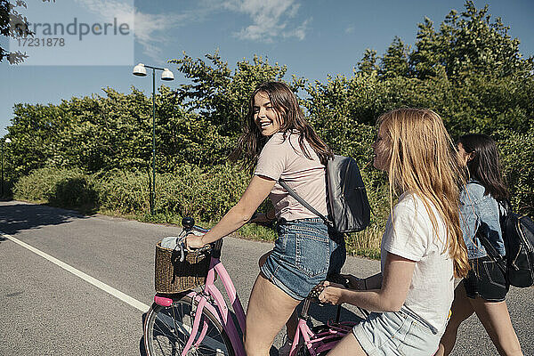 Weibliche Teenager Radfahren auf der Straße während sonnigen Tag