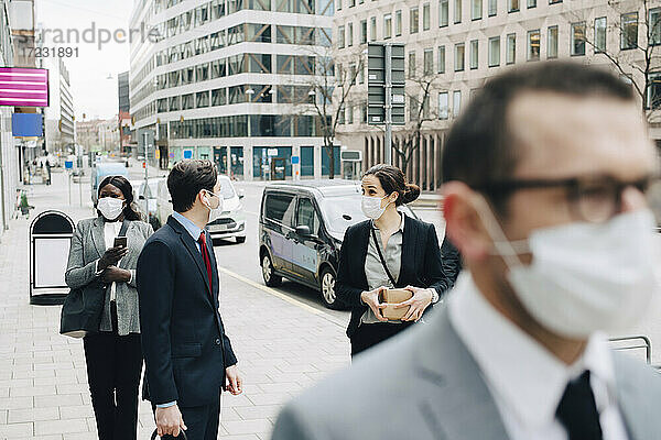 Geschäftsleute im Gespräch auf dem Fußweg in der Stadt während der Pandemie