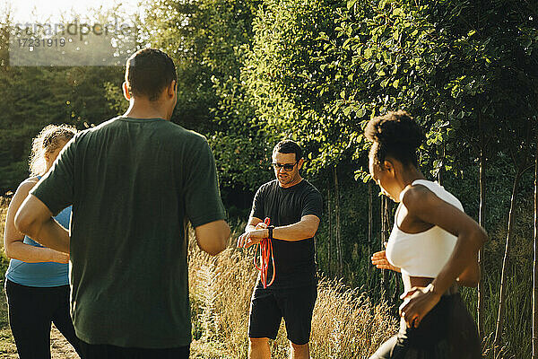Fitness-Instruktor trainiert männliche und weibliche Athleten beim Training im Park