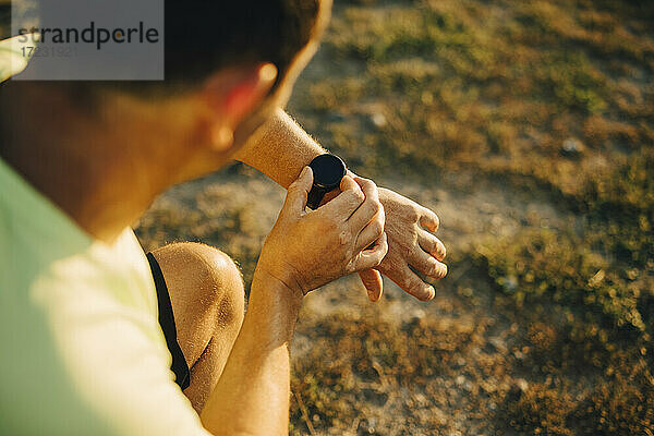 Ausgeschnittenes Bild eines Sportlers  der die Zeit auf seiner Armbanduhr überprüft