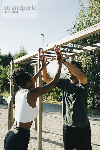 Männliche und weibliche Athleten geben sich im Park die Hand