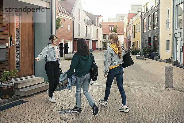 Freundinnen grüßen auf dem Fußweg vor dem Haus