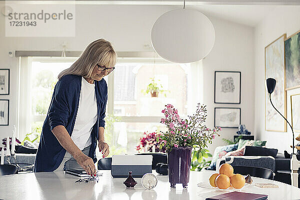 Blonde Frau mit In-Ear-Kopfhörern schaut auf ein digitales Tablet im Wohnzimmer