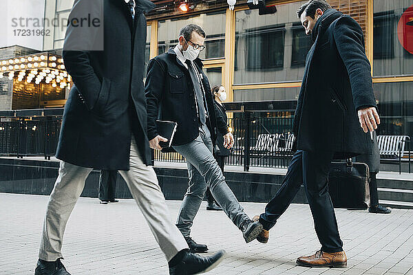 Geschäftsleute grüßen mit Fußtapfen auf dem Fußweg in der Stadt während der Pandemie