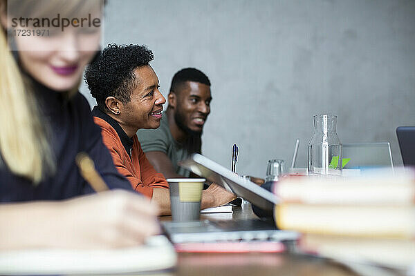 Lächelnde männliche und weibliche Kollegen in der Diskussion während der Sitzung im kreativen Büro