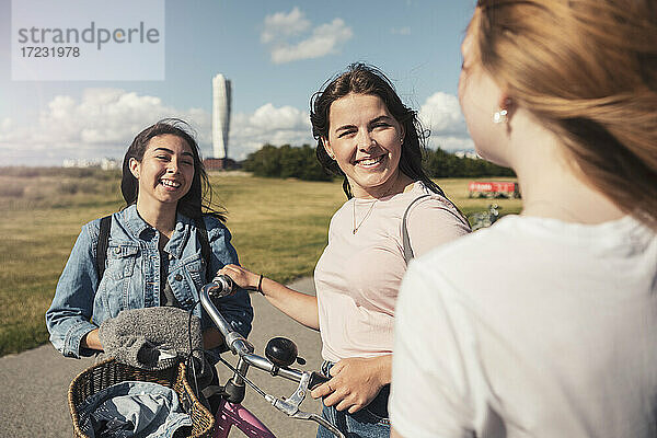 Lächelnde weibliche Teenager im Gespräch mit einander im Park während sonnigen Tag