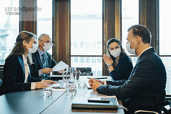 Männliche und weibliche Kollegen diskutieren im Sitzungssaal im Büro während COVID-19