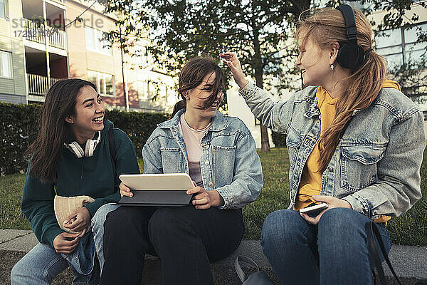 Weibliche Freunde mit digitalen Tablette sitzen im Park