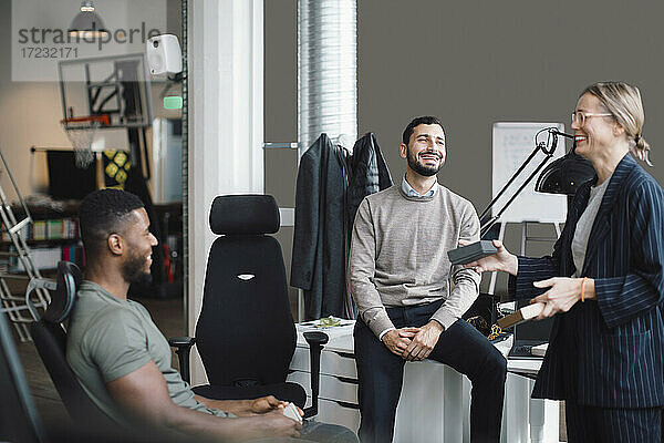 Weibliche und männliche Kollegen lachen beim Diskutieren über Produkt bei kreativen Büro