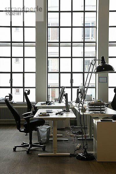 Interieur eines kreativen Büros mit Schreibtischen und Lampe