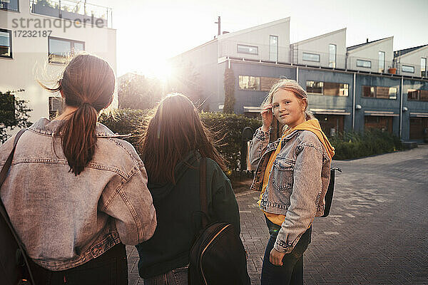 Freundinnen stehen bei Sonnenuntergang auf dem Fußweg vor einem Gebäude