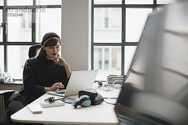 Weibliche Unternehmerin arbeitet am Laptop  während sie am Schreibtisch im Büro sitzt