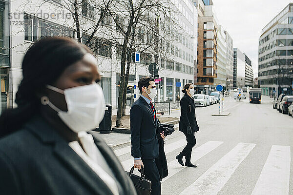 Weibliche und männliche Kollegen beim Überqueren der Straße in der Stadt während der Pandemie