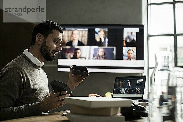 Männlicher Unternehmer  der den Kunden per Videokonferenz auf dem Laptop im Büro etwas über das Produkt erklärt