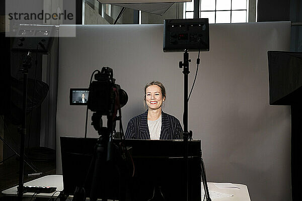 Lächelnde weibliche Unternehmerin Videoaufnahme auf Fernsehkamera im Büro