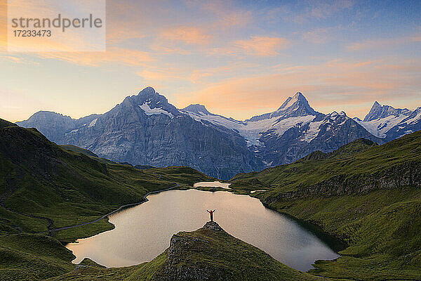 Fröhlicher Wanderer mit Blick auf Wetterhorn  Schreckhorn und Finsteraarhorn vom Bachalpsee in der Morgendämmerung  Berner Oberland  Schweiz  Europa