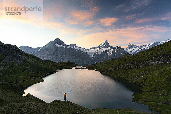 Wanderer bewundert den Sonnenaufgang vom Ufer des Bachalpsees  Grindelwald  Berner Oberland  Kanton Bern  Schweiz  Europa