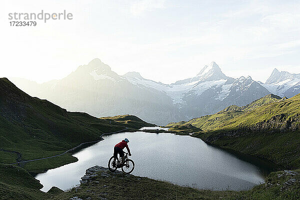 Mountainbiker fahren bergab am Bachalpsee in der Morgendämmerung  Grindelwald  Berner Oberland  Kanton Bern  Schweiz  Europa