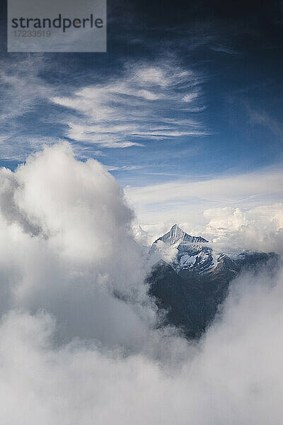 Sonnenlicht über dem Weisshorn-Gipfel  der aus einem Wolkenmeer auftaucht  Kanton Wallis  Schweiz  Europa